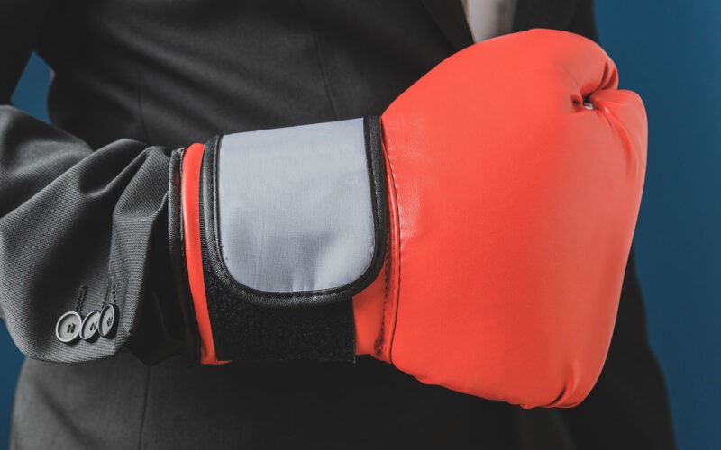 Person in business suit with bright red boxing glove